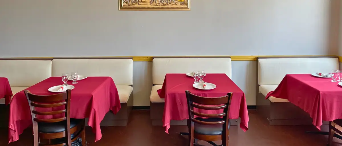 The Delhi Palace dining room in Brantford, with red linen tables, cream booth seating and framed Indian artwork