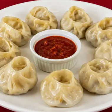 A plate of hand folded steamed momos served with red chilli dipping sauce