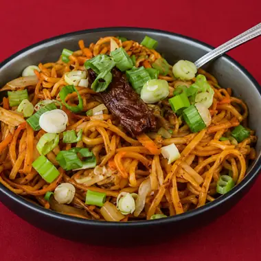Wok tossed hakka noodles topped with chilli chicken and spring onion