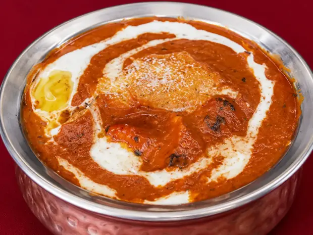Butter chicken swirled with cream, served in a hammered copper bowl
