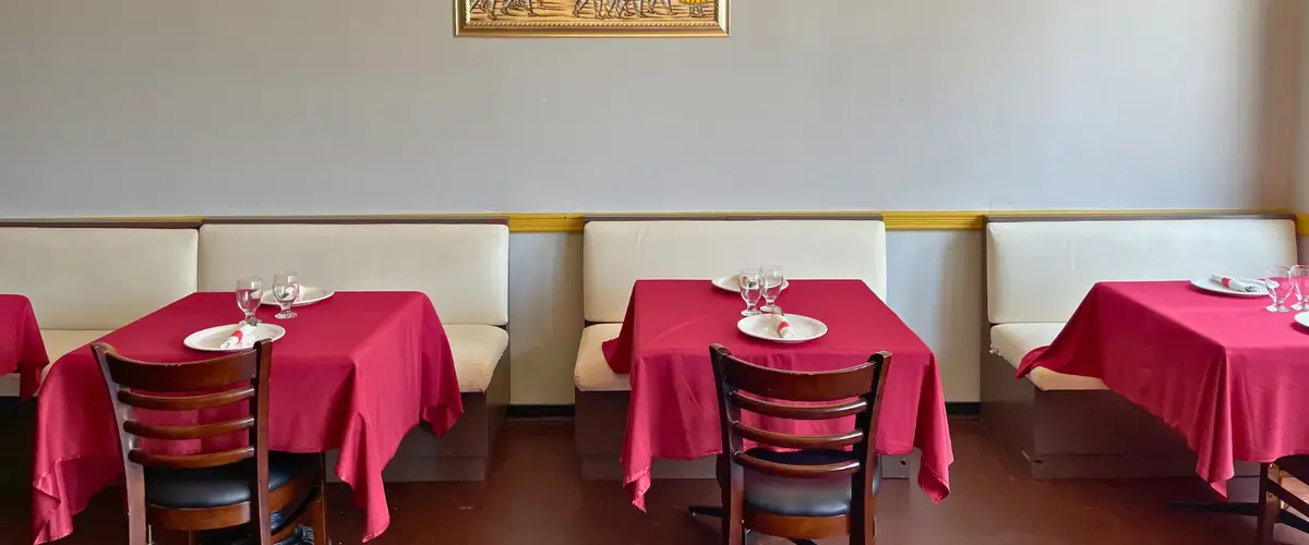 The Delhi Palace dining room in Brantford, with red linen tables, cream booth seating and framed Indian artwork