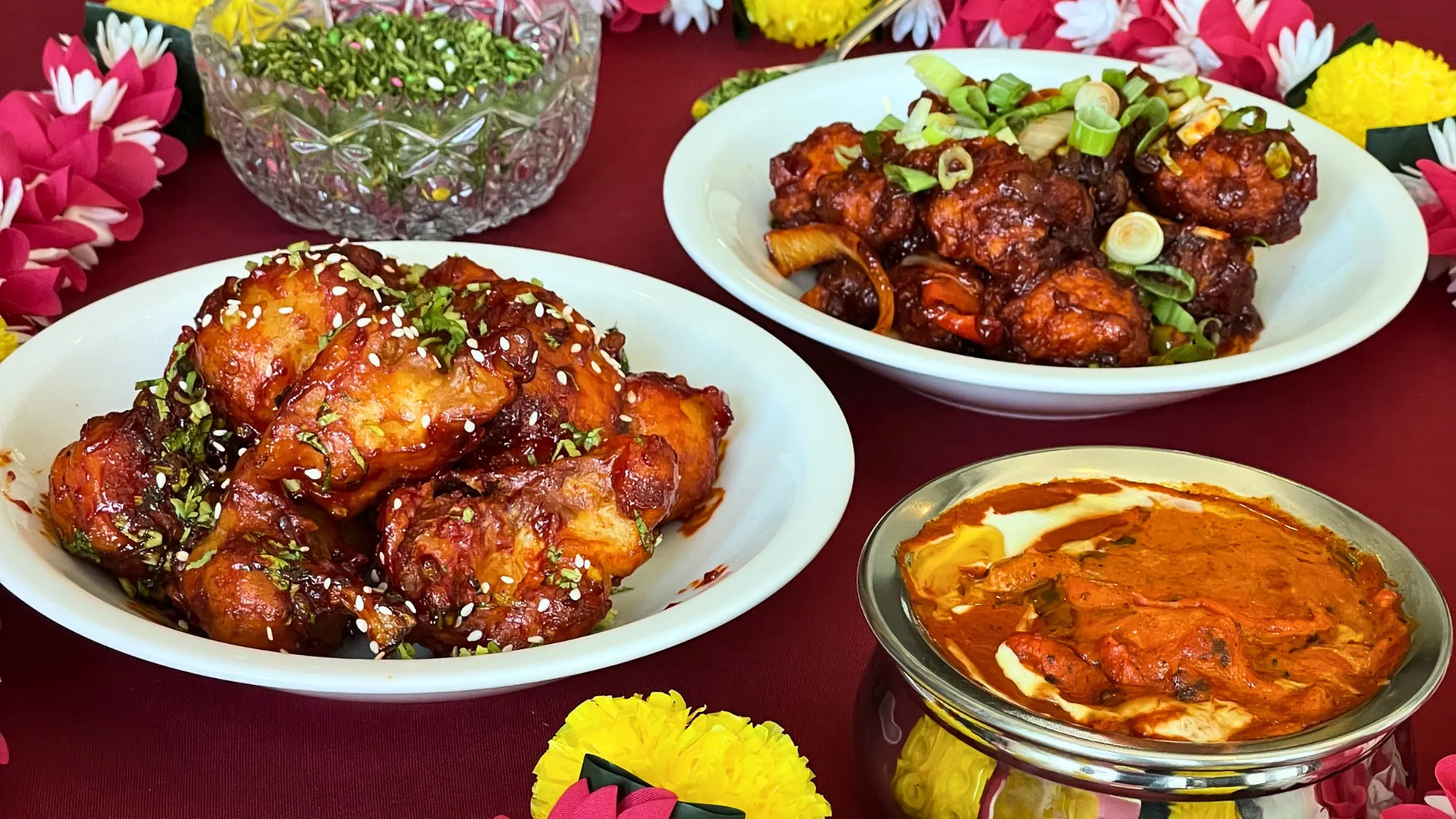 A celebration table at Delhi Palace with honey chilli chicken, Manchurian, butter chicken and marigold garlands