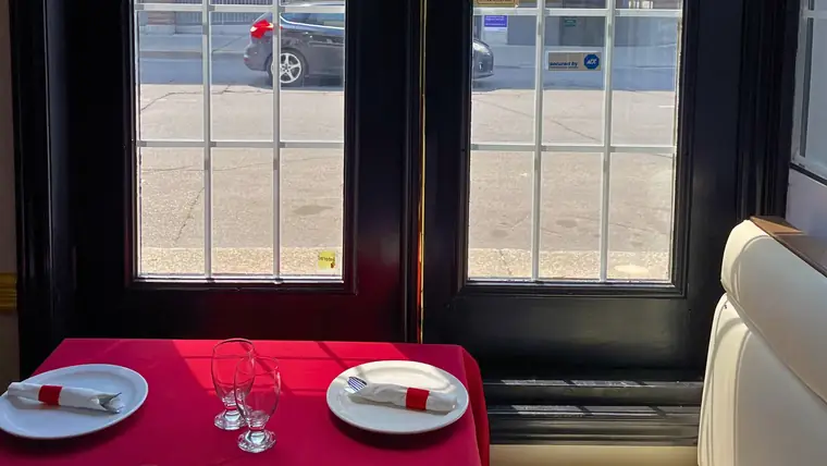 A window table set with red linen, glassware and folded napkins