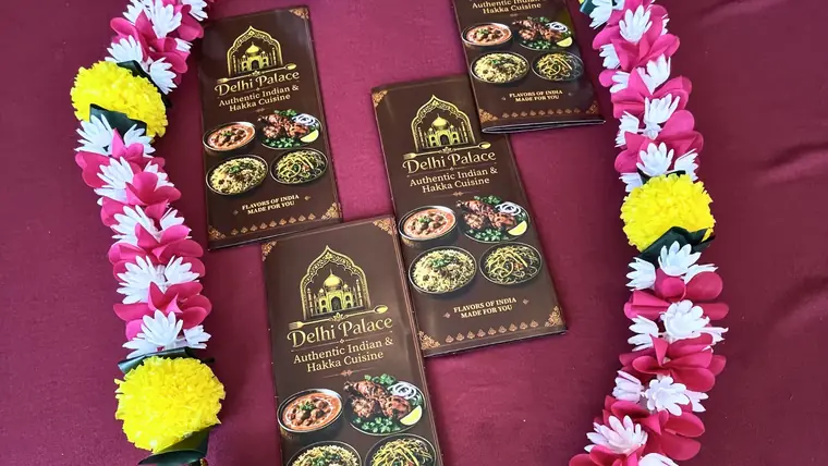Delhi Palace menu cards laid out with marigold and rose garlands