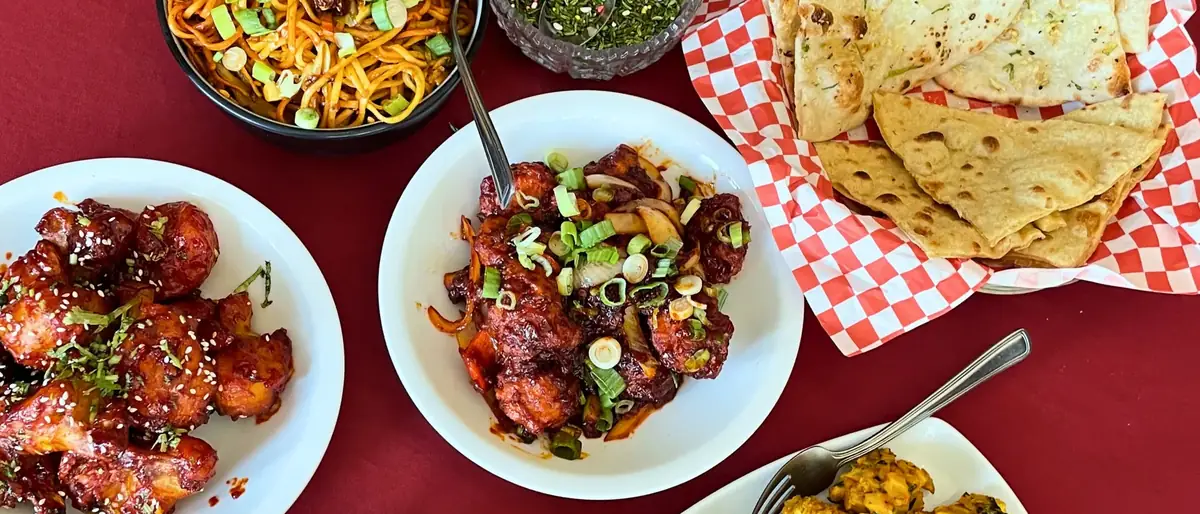 A full table spread at Delhi Palace with hakka noodles, chilli chicken, vegetable pakora and fresh naan