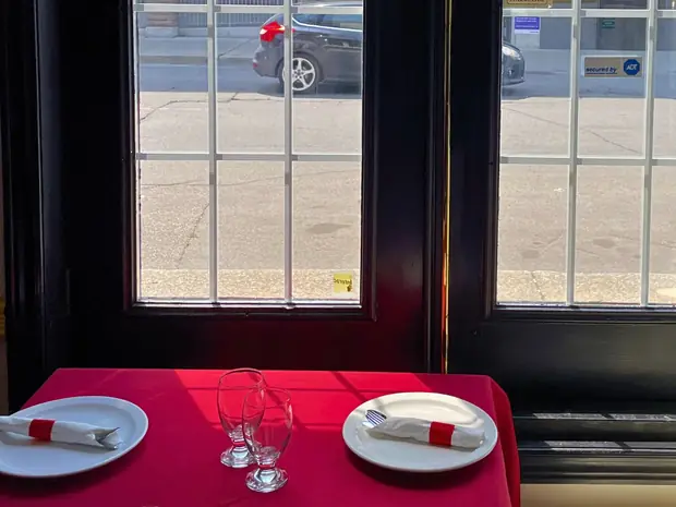 A window table set with red linen, glassware and folded napkins in the Delhi Palace dining room