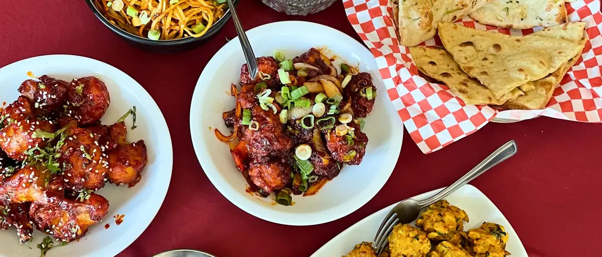 A full table spread at Delhi Palace with hakka noodles, chilli chicken, vegetable pakora and fresh naan