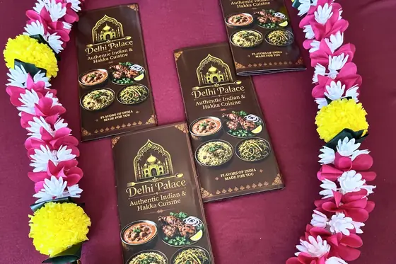 Delhi Palace menu cards laid out with marigold and rose garlands