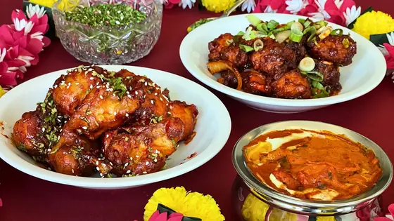 Tandoori wings, chilli chicken and a copper bowl of curry laid out on a red table at Delhi Palace